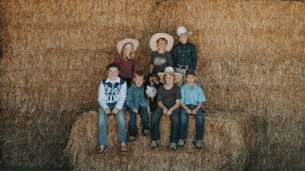 Group of kids sitting on hay bales wearing outfits from Moonstone Trading Co